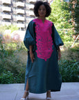 Model wearing luxurious teal Boubou dress with bold pink embroidery and voluminous sleeves.