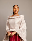 A lady wearing the Queen Ire two-piece set with textured ivory cape top and wine maxi skirt decorated with golden tassels, styled for weddings and cultural celebrations.
