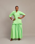 A lady wearing the Ine maxi dress  featuring a draped V neckline, gathered waist detailing, and ruched hem accents.
