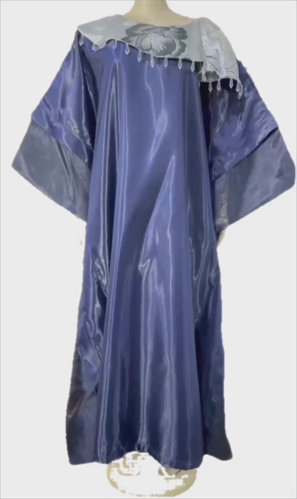 Woman wearing a shiny metallic blue-green cupped chain dress with loose sleeves and embellished neckline.
